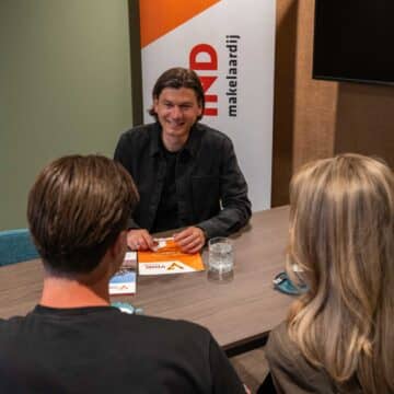 Adviseur van VIND Makelaardij bespreekt aan tafel de bouwplannen met twee klanten.