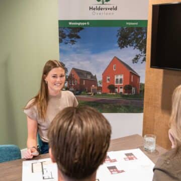 Adviseur bespreekt woningplannen van project Heldersveld Overloon met twee klanten aan tafel.