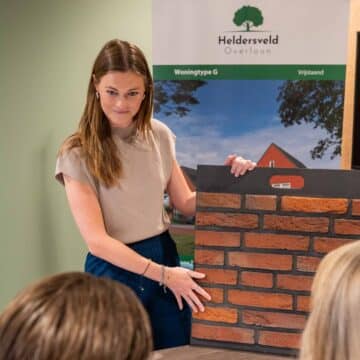 Adviseur toont bakstenen gevelmonster aan klanten bij woningproject Heldersveld in Overloon.