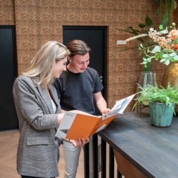 Een adviseur en klant bekijken samen een brochure van VIND in een modern kantoor.