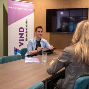 Adviseur van VIND financieel advies in gesprek met twee klanten aan een vergadertafel