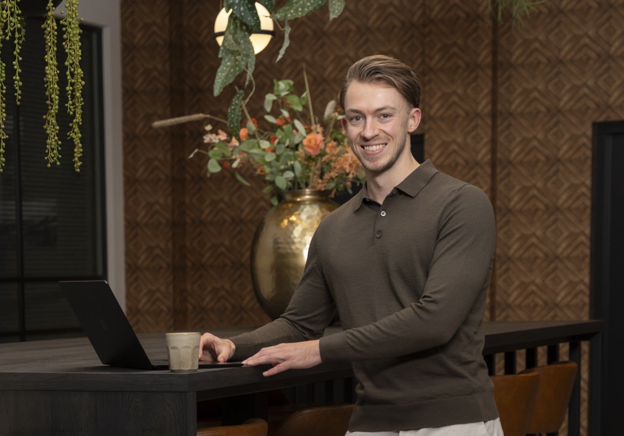 Jef met een laptop en een kop koffie aan een tafel