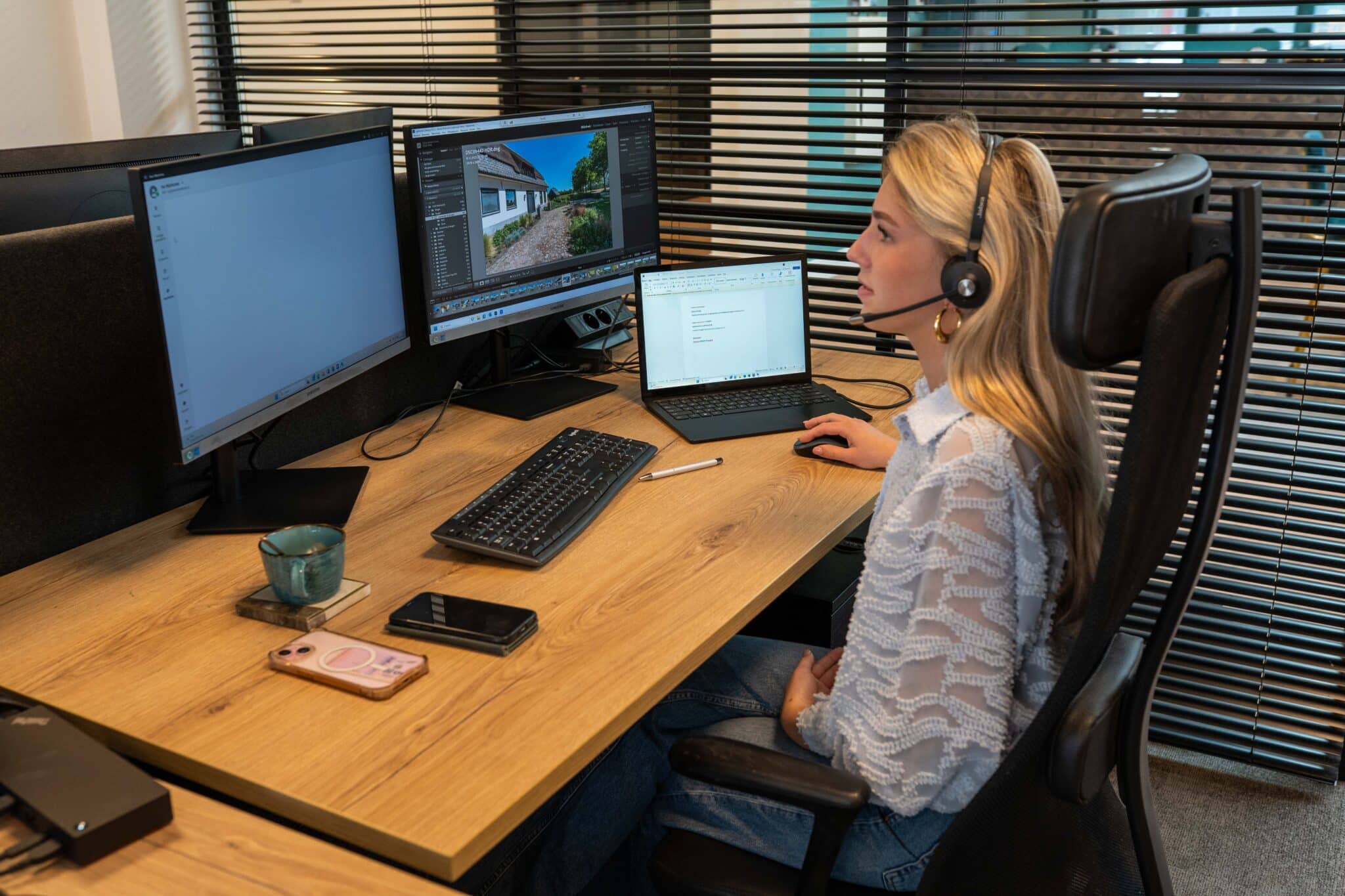 Isa met headset achter haar beeldschermen in het VIND-kantoor